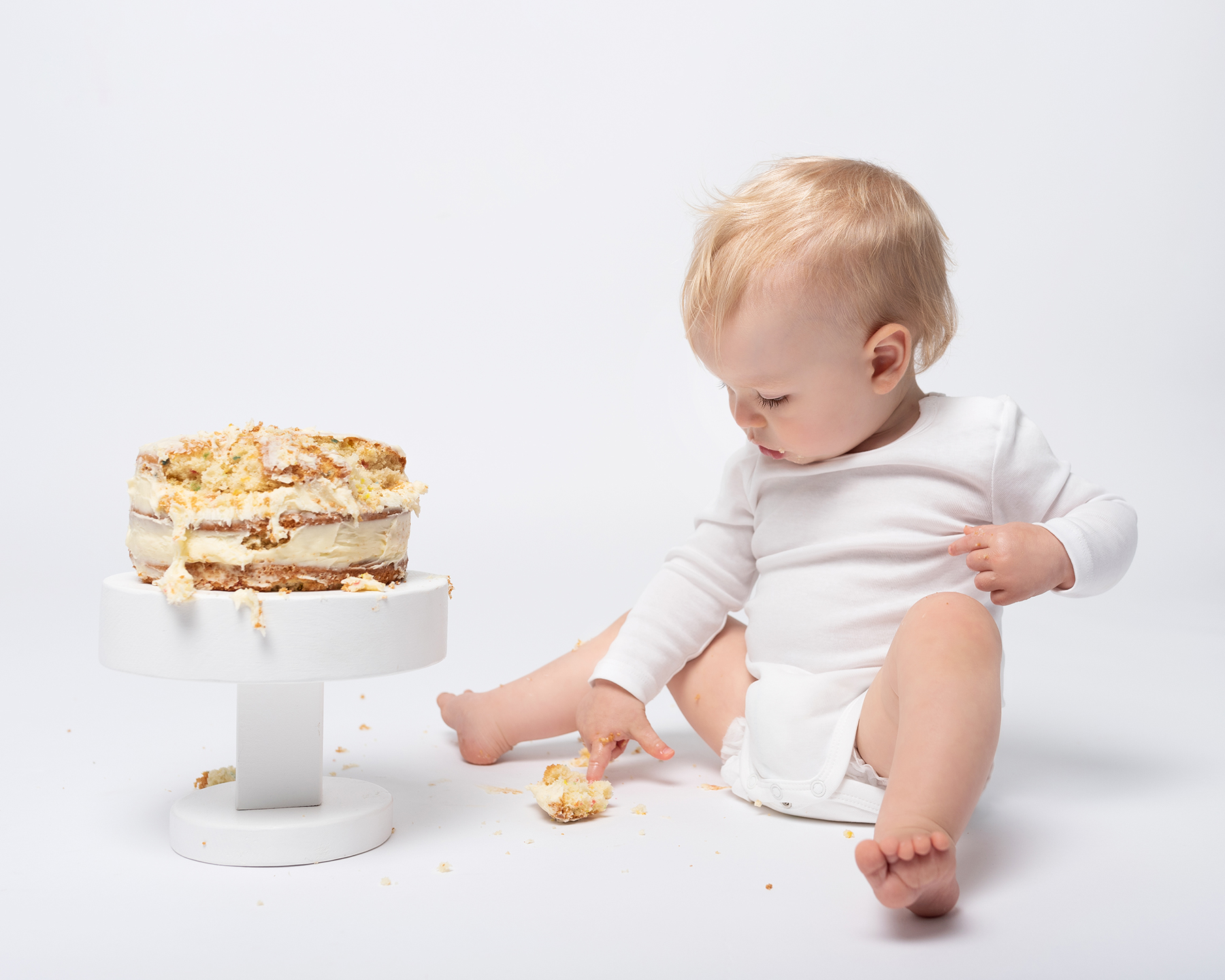 Baby explores birthday cake on a photoshoot in Sandwich Kent