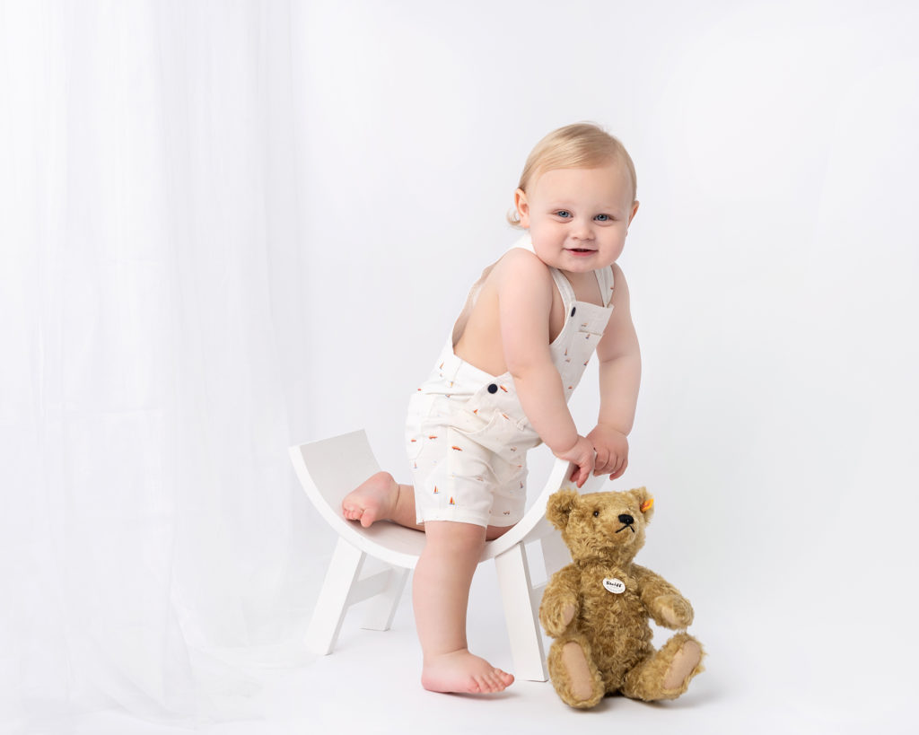 baby boy in white dungarees by Baby Photographer in Canterbury, Kent