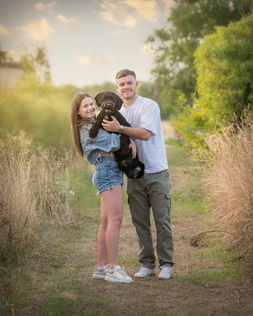 Girl and boy smiling while holding a pet dog on a outdoor family photoshoot in Kent