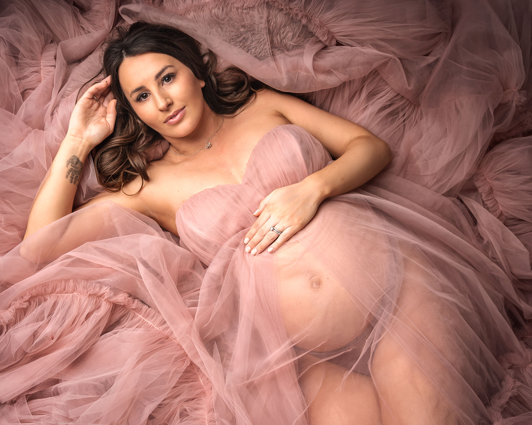 Pregnant women laying down in a pink dress Maternity Photographer Canterbury