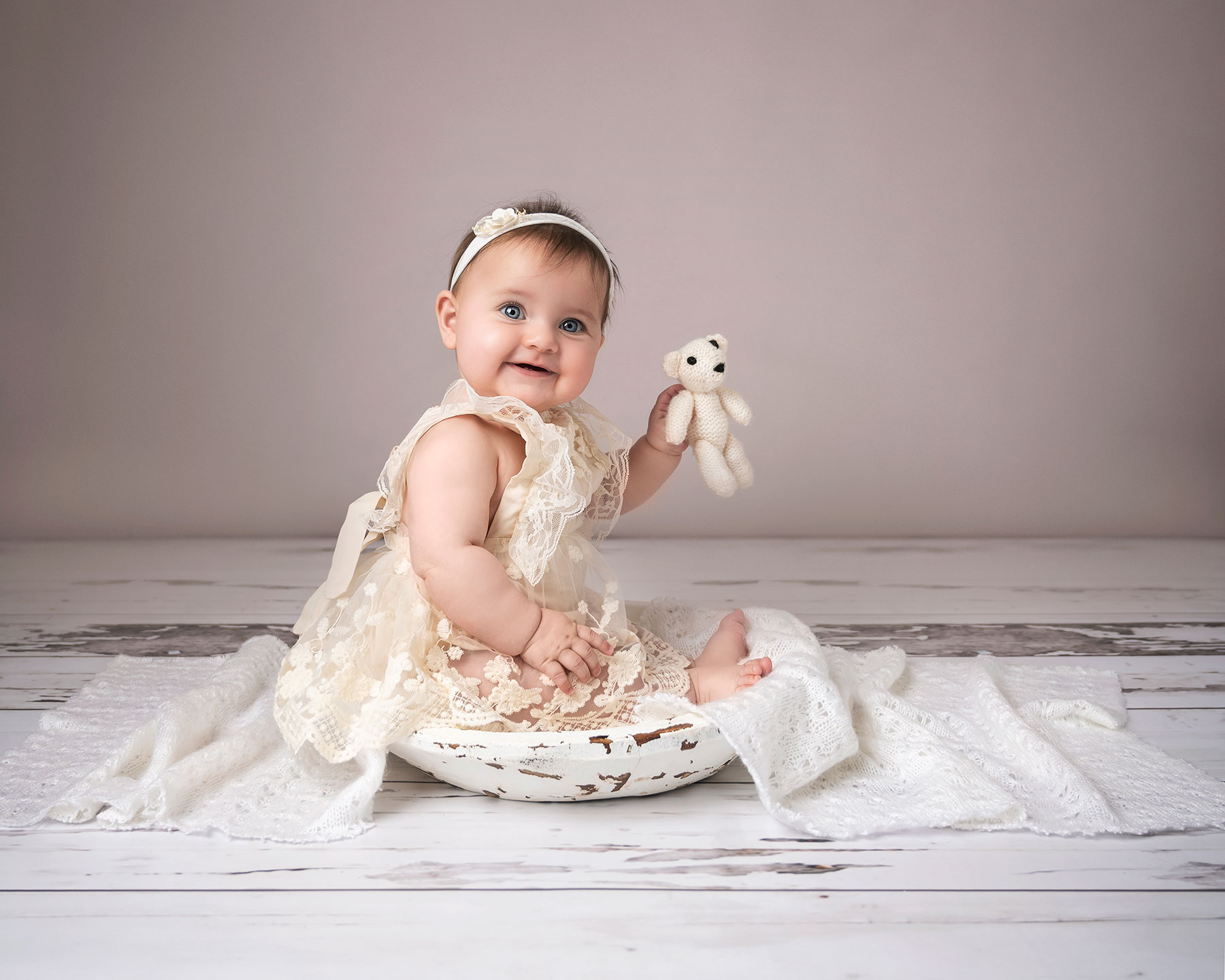 baby girl smiling while holding a teddy on a photography session in Kent