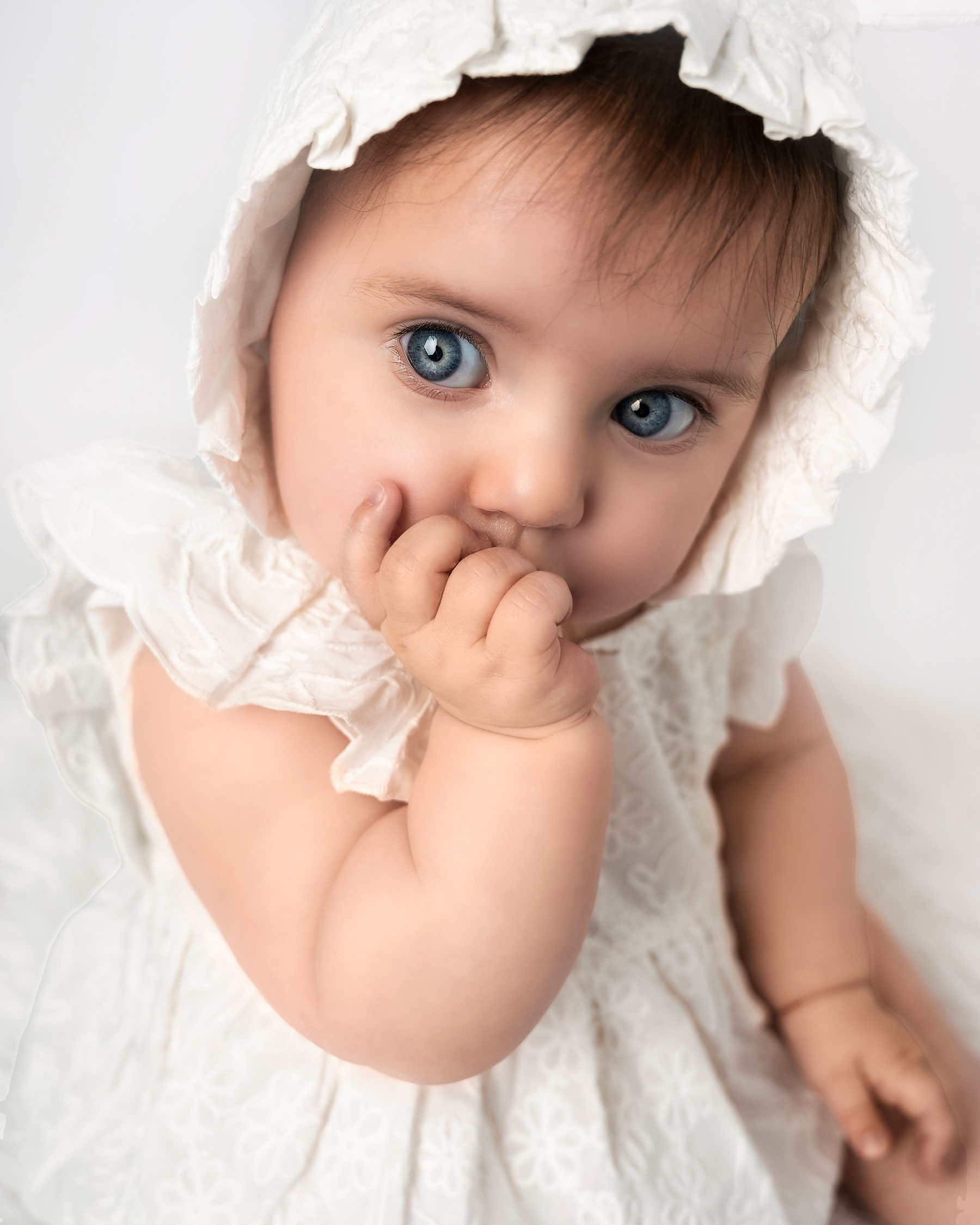 baby girl with big eyes sucking her thumb on a photography session in Kent