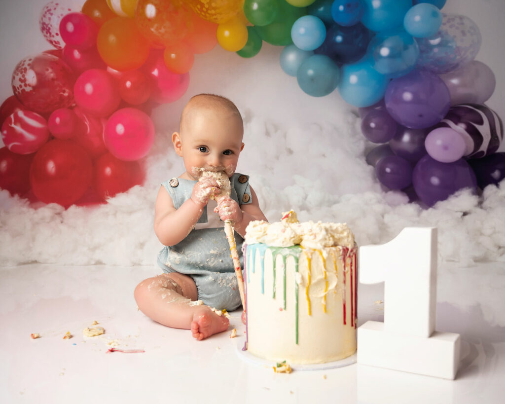baby boy eating a rainbow cake on a cake smash photoshoot in Kent